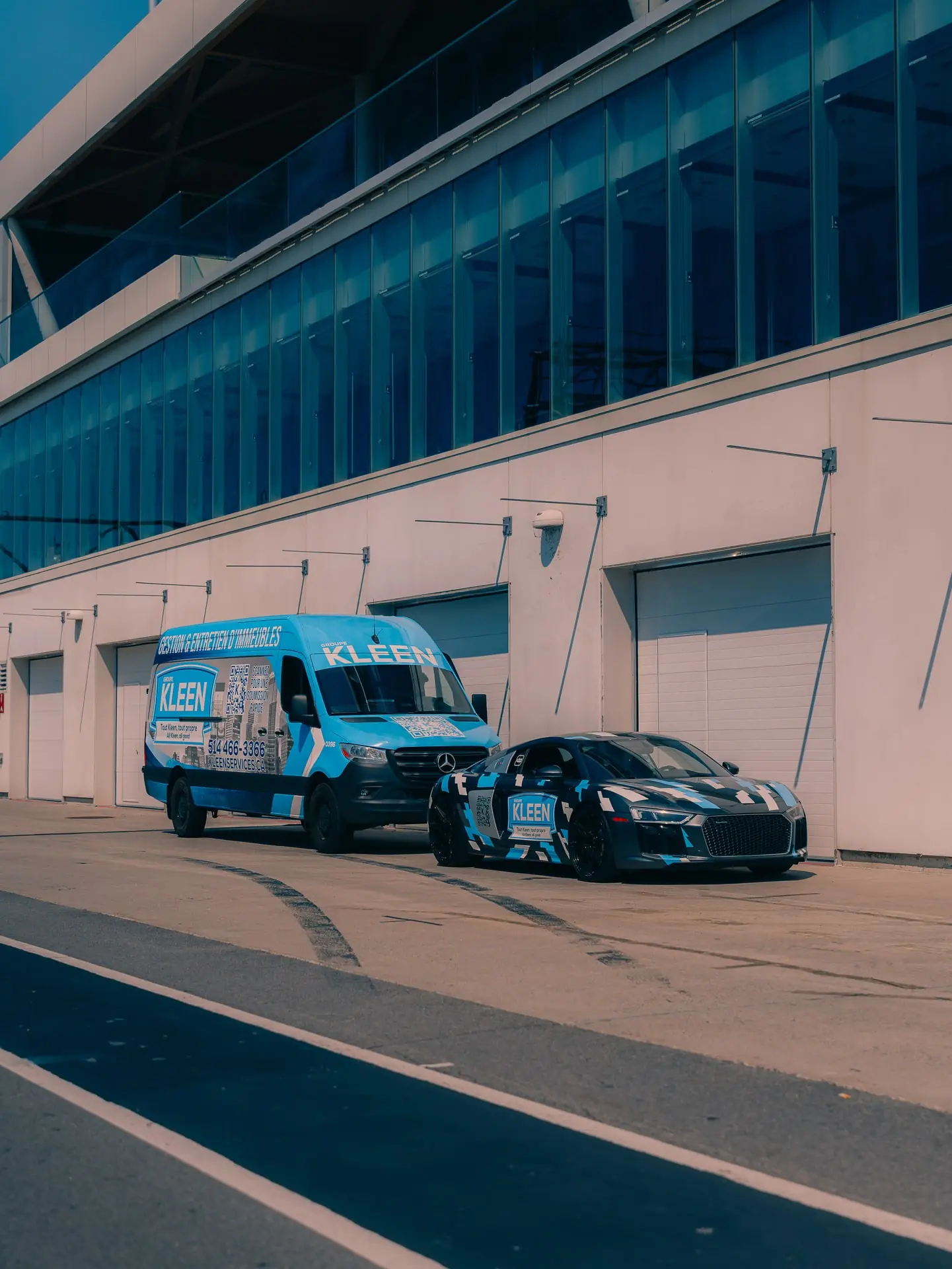 KLEEN van and car outside the doors of a large building