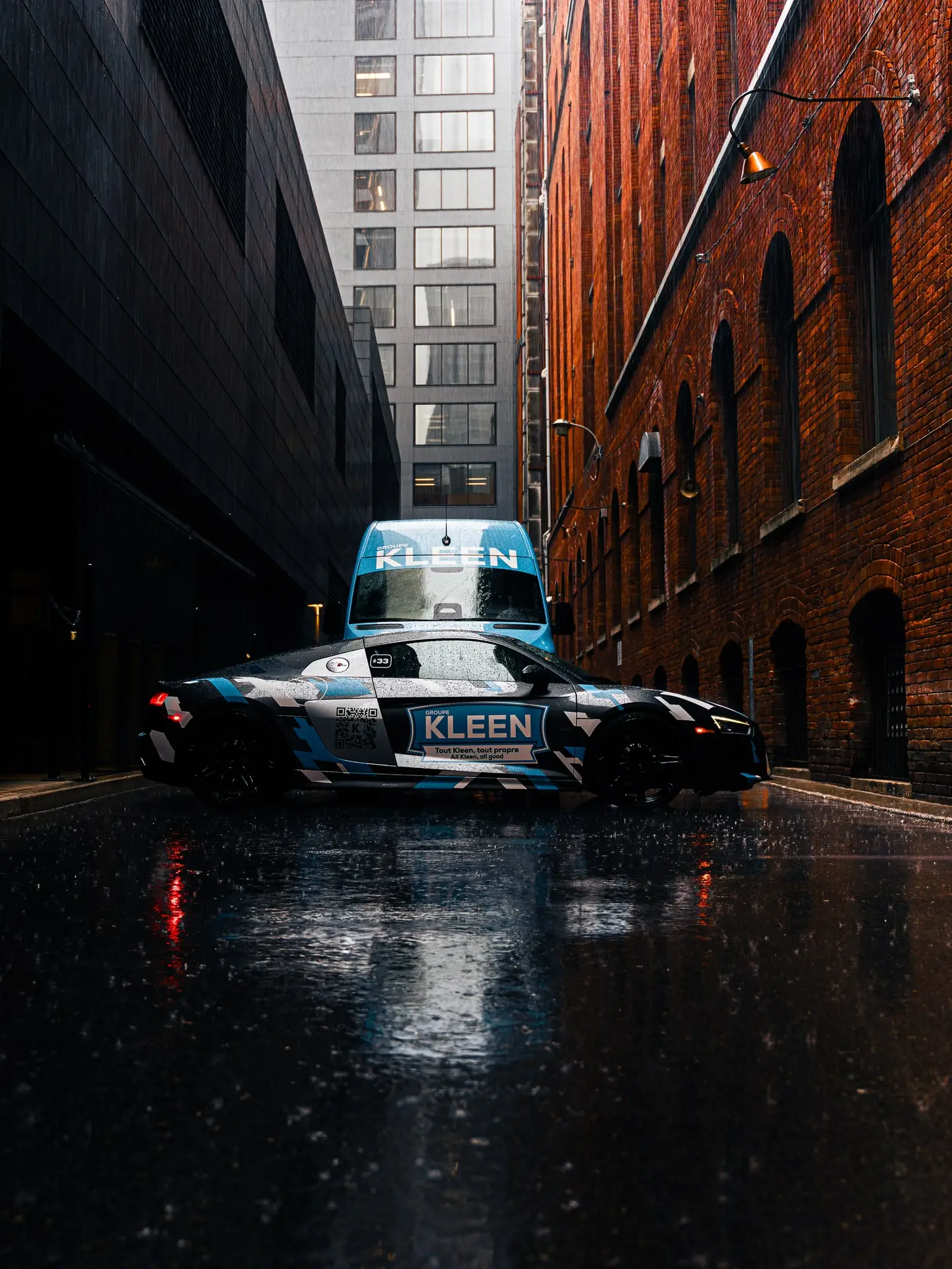 KLEEN vehicles and their reflections on a wet alley surface