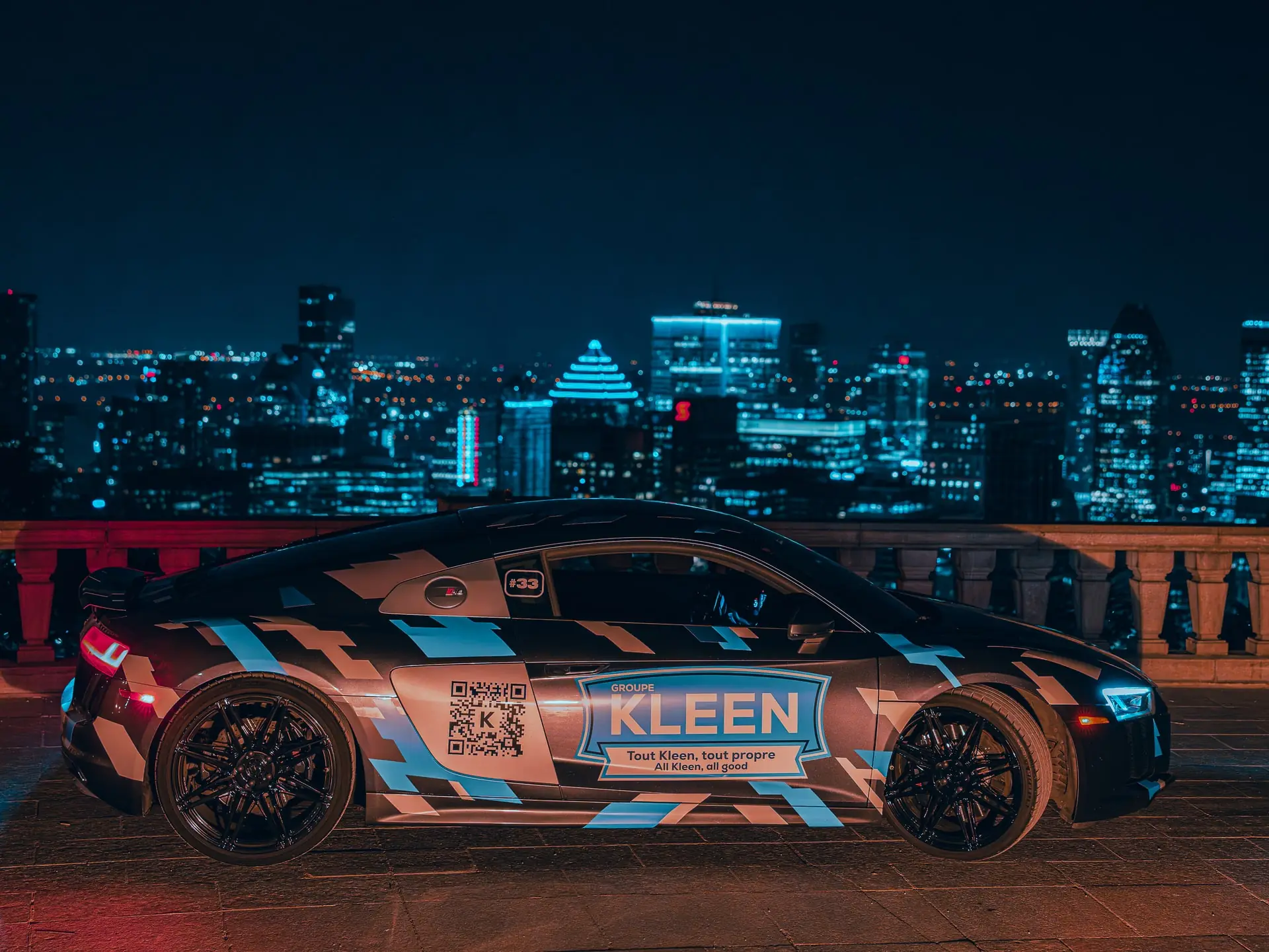 Side view of a KLEEN-branded car against the illuminated city